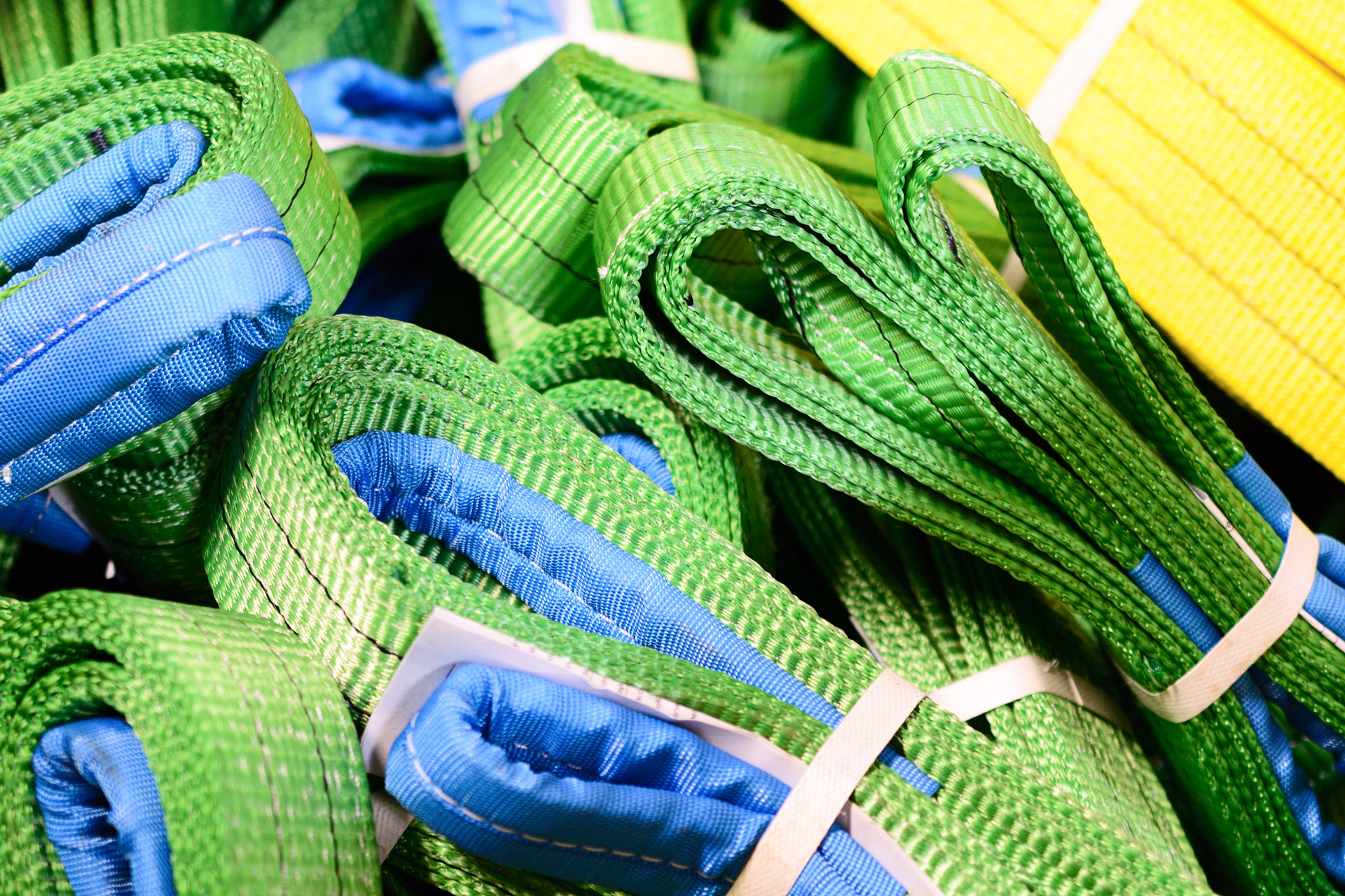 Green nylon lifting slings stacked in piles.